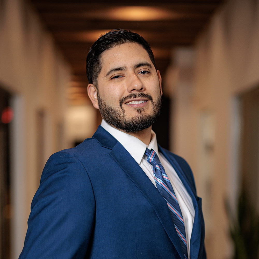 Roy, co-founder of Guapo Essentials, dressed in a suit, sitting confidently in a modern co-working space.